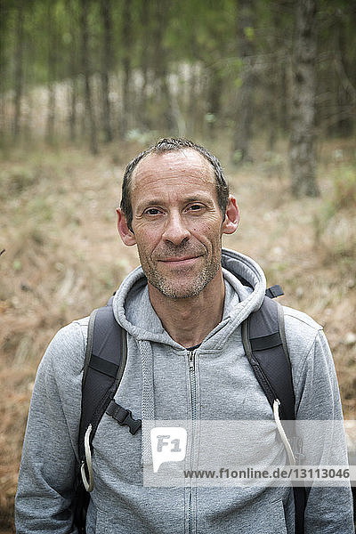 Porträt eines selbstbewussten Wanderers mit Kapuzenjacke im Wald