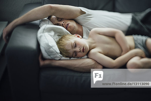 Hochwinkelansicht von Vater und Sohn  die zu Hause auf dem Sofa schlafen