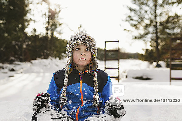 Portrait of girl sitting on snow covered field