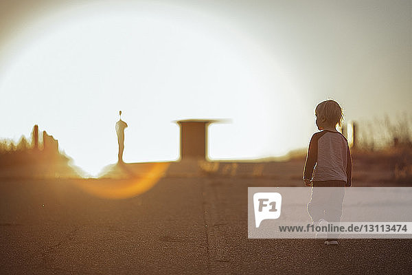 Rear view of boy walking on road