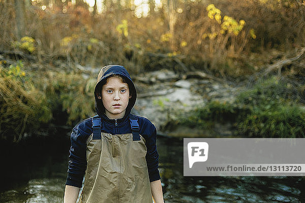 Porträt eines Jungen  der im See am Wald steht