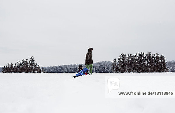 Vater mit Kindern auf schneebedecktem Feld gegen den Himmel