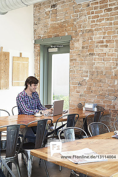 Mann benutzt Laptop  während er im Café sitzt