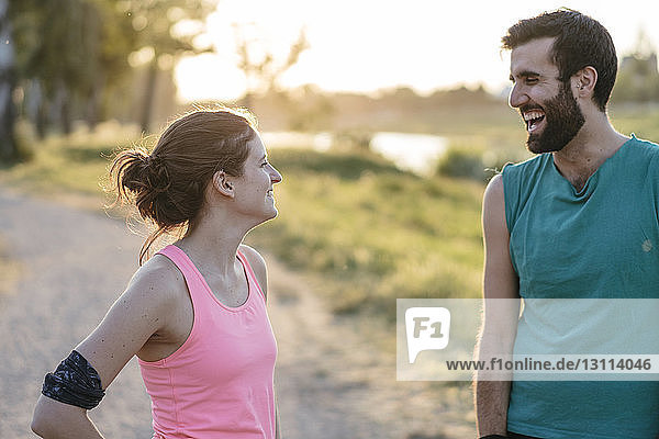 Glückliches Paar steht sich beim Sport im Park gegenüber
