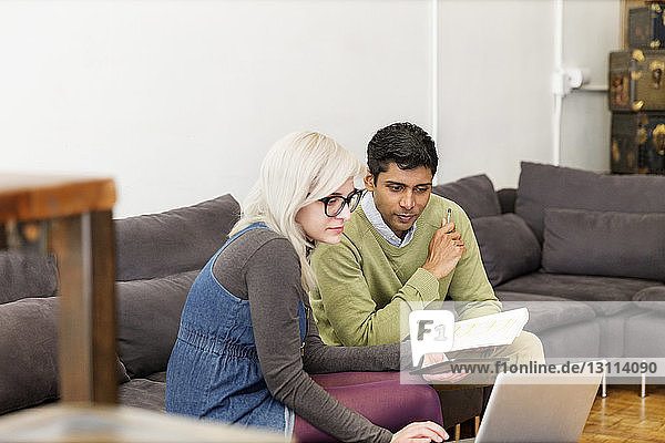 Geschäftsleute  die während einer Besprechung im Kreativbüro einen Laptop benutzen