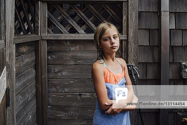 Porträt eines Mädchens mit Handtuch vor einem Blockhaus stehend