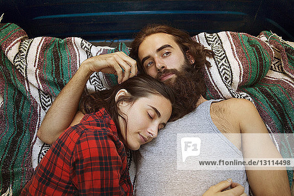 Overhead view of woman sleeping with thoughtful man in pick-up truck
