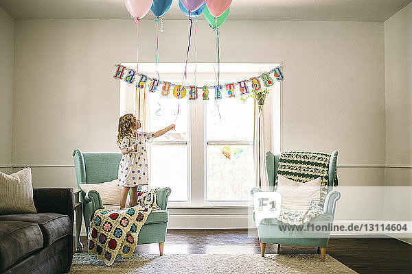 Mädchen dekoriert Luftballons im Wohnzimmer für Geburtstagsfeier