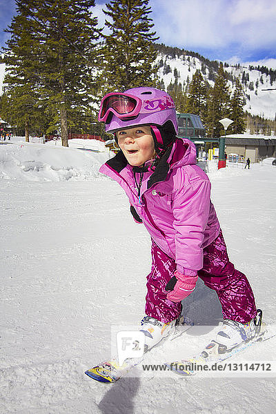 Happy girl skiing on snow covered field