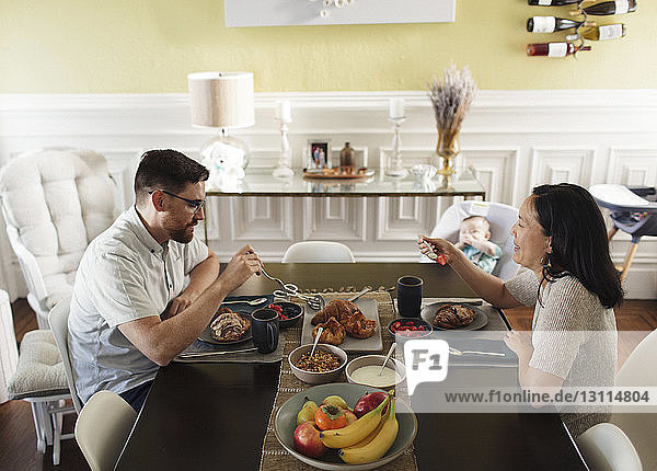 High angle view of parents having breakfast while sitting by daughter at dining table