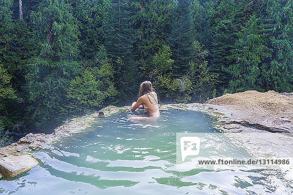 Woman swimming in hot spring at forest