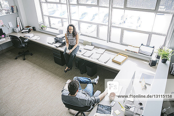 Scharfer Blick auf Geschäftsleute  die an Schreibtischen im Büro sitzen und reden