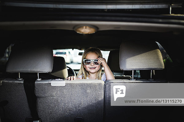 Porträt eines Mädchens mit Sonnenbrille  das im Auto sitzt