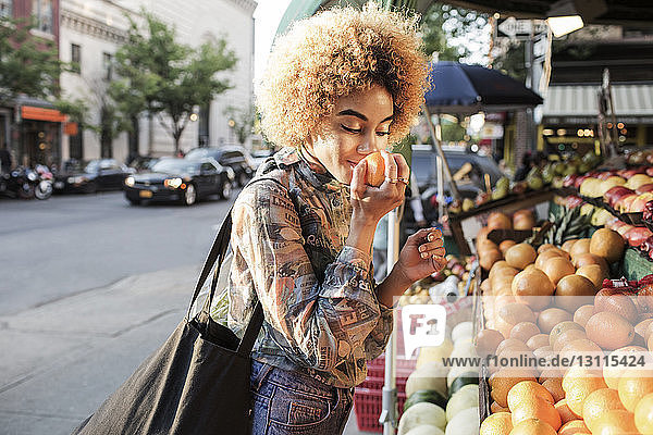 Woman smelling fresh orange at market stall