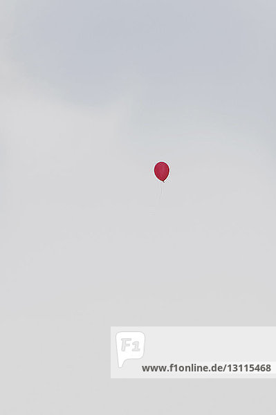 Tiefwinkelansicht eines roten Heliumballons in der Luft gegen den Himmel