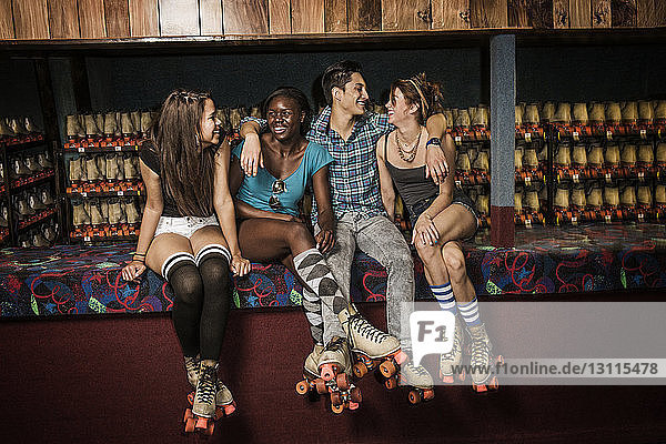 Lächelnde Freunde sitzen im Club gegen Rollschuhe