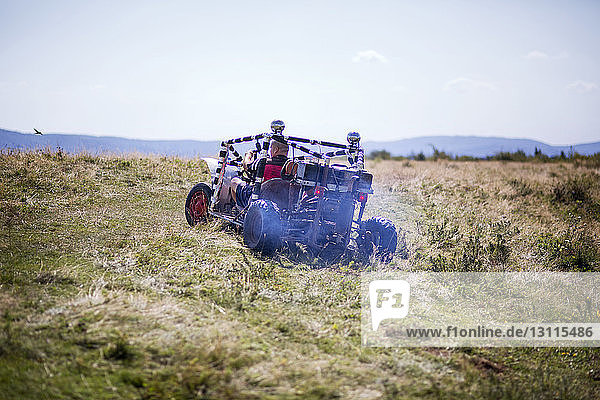 Rear view of man riding off-road vehicle on field