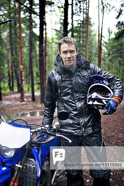 Porträt eines Motorradfahrers im Wald stehend