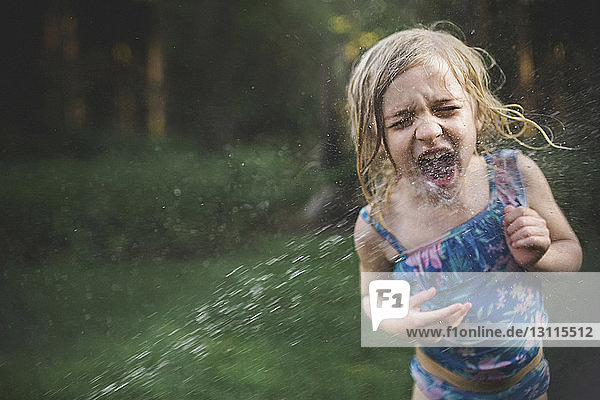 Girl enjoying in water spray at backyard