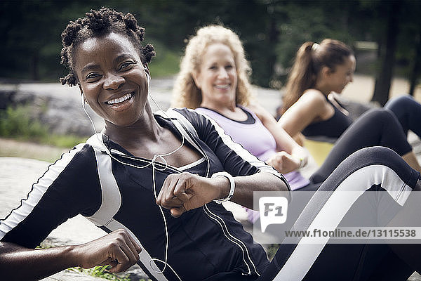 Portrait of happy sportswoman with friends exercising at park