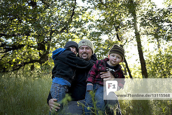 Portrait of happy father with sons on grassy field