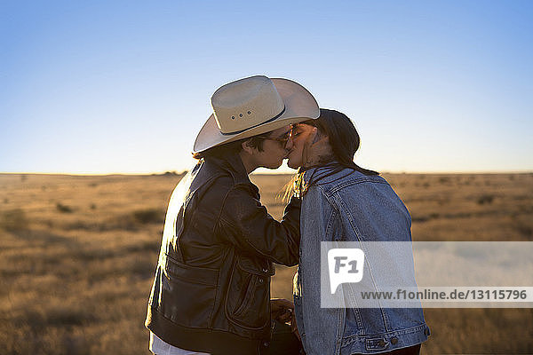 Seitenansicht eines Paares  das sich auf dem Spielfeld vor klarem Himmel küsst
