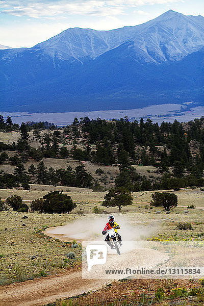 Man riding motorcycle on dirt road against mountain