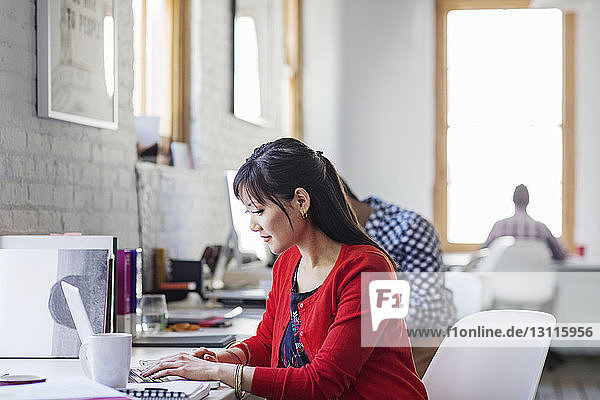 Businesswoman using laptop while working in office