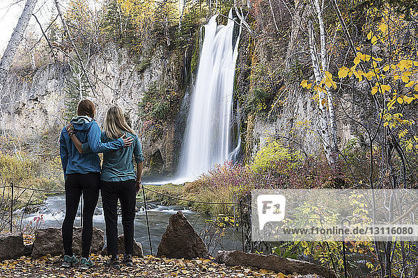 Mutter und Tochter schauen in voller Länge auf den Wasserfall  während sie im Wald im Badlands-Nationalpark stehen