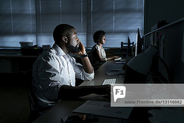 Colleagues working on desktop computers in office
