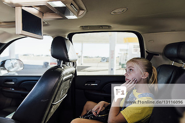 Girl watching television while sitting in car