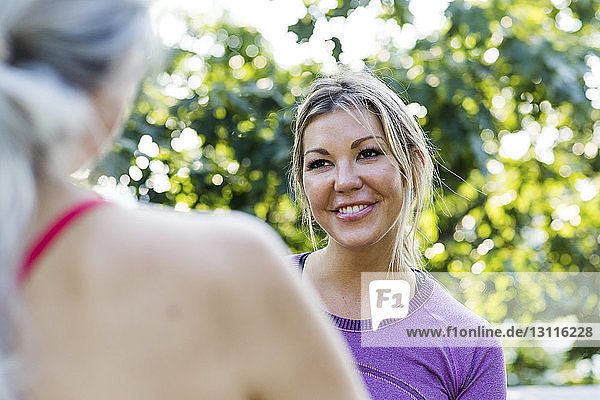 Lächelnde Frau sieht Freundin im Park an