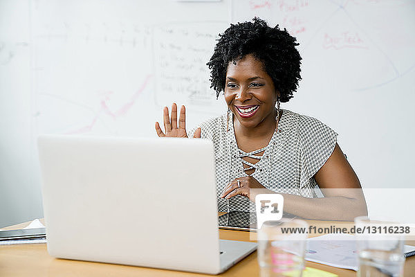 Lächelnde Geschäftsfrau benutzt Laptop-Computer  während sie im Sitzungssaal im Büro sitzt