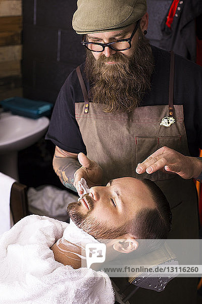Hochwinkelansicht eines Barbiers  der Rasierschaum auf den Kunden aufträgt