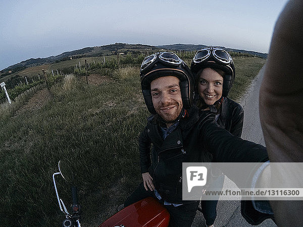 Hochwinkelporträt eines glücklichen jungen Paares auf einem Motorrad