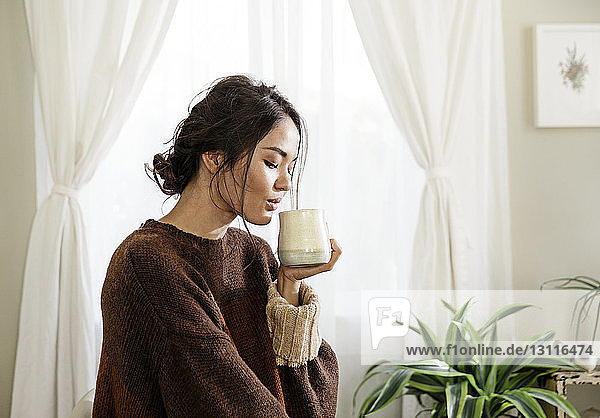 Junge Frau trinkt zu Hause Kaffee