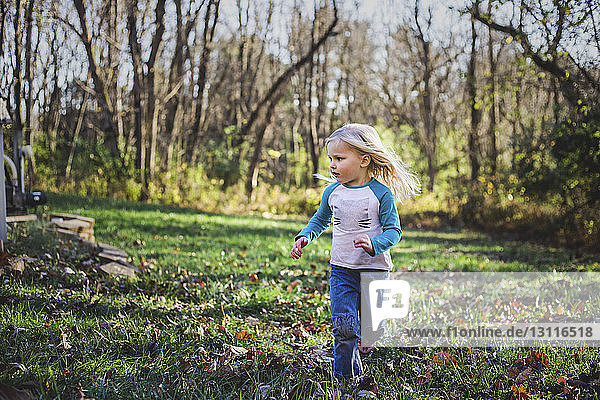 Mädchen rennt im Herbst auf Grasfeld im Park