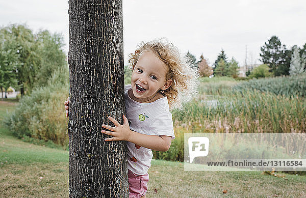 Porträt eines niedlichen glücklichen Mädchens  das am Baum im Park steht