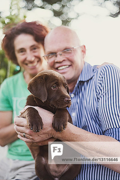 Portrait of smiling mature couple with dog in yard