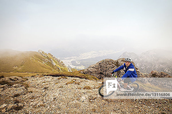 High angle view of athlete riding bicycle on mountain against sky