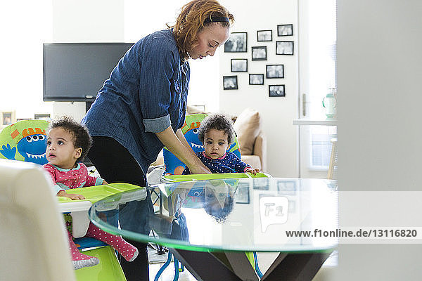 Mother fixing high chair for baby girl