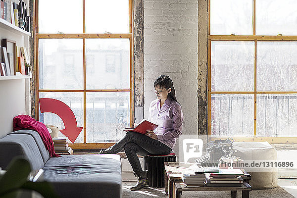 Businesswoman writing in book while sitting in creative office