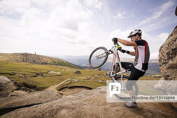 Man performing wheelie on mountain against sky