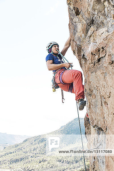 Niedrigwinkelansicht einer Wanderin  die beim Klettern am Berg ein Seil benutzt