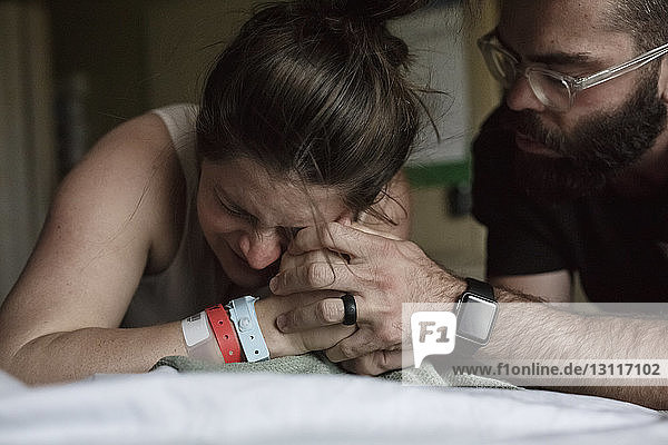 Close-up of man comforting painful pregnant woman on hospital bed