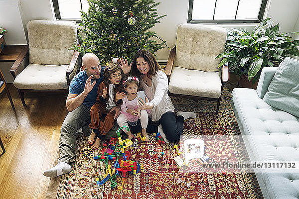 Fröhliche Familien-Videokonferenzen  während man zu Hause am Weihnachtsbaum sitzt