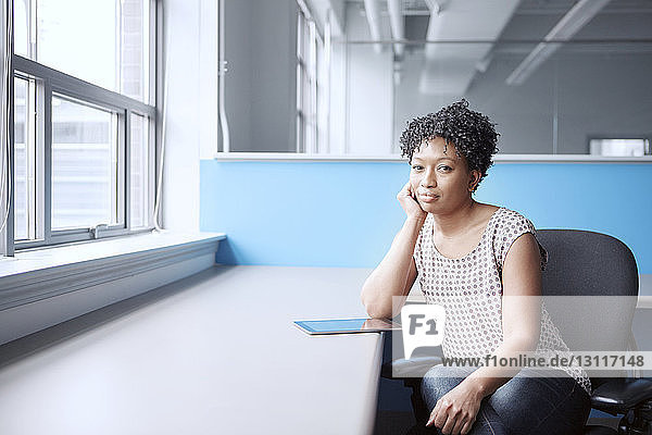 Portrait of confident businesswoman sitting on chair by window in office