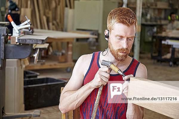 Carpenter wearing earphones while working in workshop