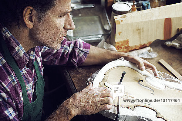 Hochwinkelaufnahme eines Geigenbauers in der Werkstatt