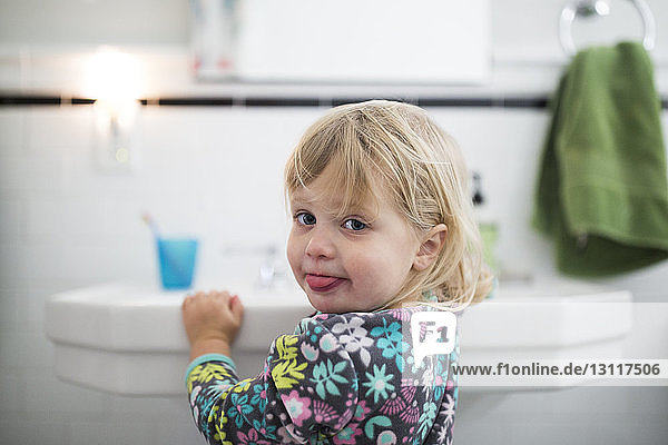 Portrait of baby girl standing by sink in bathroom